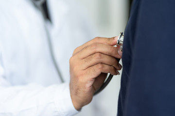 Close up of a doctor holding stethoscope checking patient heartbeat.