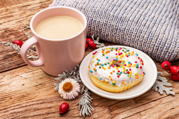 Hot coffee with a donut. Autumn drink for a good mood with plaid, fresh rose hips, leaves and flowers. Old wood plank background
