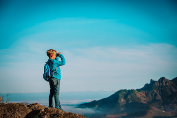 little boy with binoculars hiking in mountains