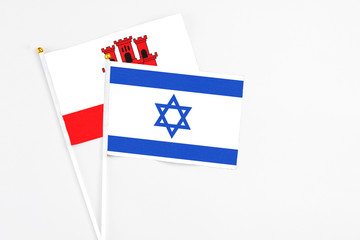 Israel and Gibraltar stick flags on white background. High quality fabric, miniature national flag. Peaceful global concept.White floor for copy space.