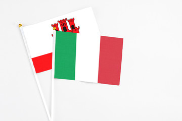 Italy and Gibraltar stick flags on white background. High quality fabric, miniature national flag. Peaceful global concept.White floor for copy space.