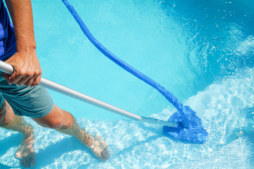 swimm pool cleaning. a man is cleaning the pool. service care