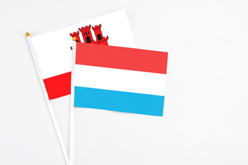 Luxembourg and Gibraltar stick flags on white background. High quality fabric, miniature national flag. Peaceful global concept.White floor for copy space.