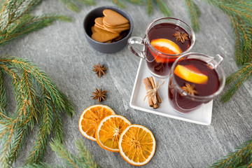 christmas and seasonal drinks concept - hot mulled wine, dry orange slices, gingerbread and...
