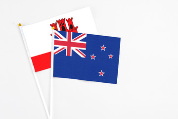 Fototapeta premium New Zealand and Gibraltar stick flags on white background. High quality fabric, miniature national flag. Peaceful global concept.White floor for copy space.
