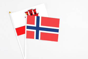 Norway and Gibraltar stick flags on white background. High quality fabric, miniature national flag. Peaceful global concept.White floor for copy space.