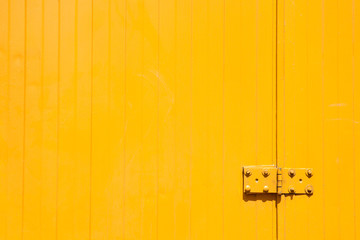 Yellow sheet metal background with old hinge. Copy space.