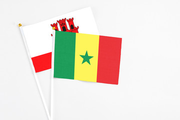 Senegal and Gibraltar stick flags on white background. High quality fabric, miniature national flag. Peaceful global concept.White floor for copy space.
