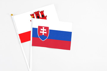 Slovakia and Gibraltar stick flags on white background. High quality fabric, miniature national flag. Peaceful global concept.White floor for copy space.