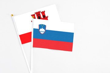 Slovenia and Gibraltar stick flags on white background. High quality fabric, miniature national flag. Peaceful global concept.White floor for copy space.
