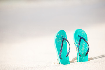 Summer mint flip flops with sunglasses on white beach