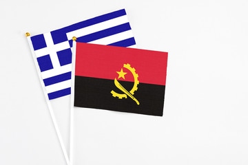 Angola and Greece stick flags on white background. High quality fabric, miniature national flag. Peaceful global concept.White floor for copy space.