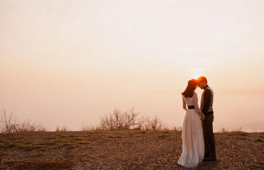 bride and groom at sunset. hugging. soft morning evening light. fog in the background. love. privacy