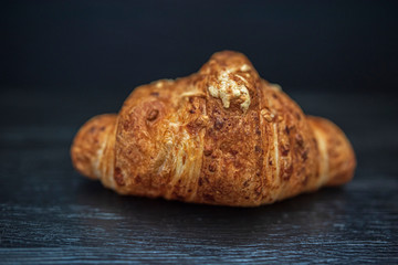 Croissant on a dark wooden background. Photographed close-up.