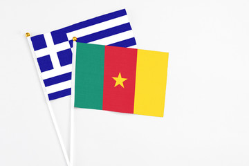 Cameroon and Greece stick flags on white background. High quality fabric, miniature national flag. Peaceful global concept.White floor for copy space.
