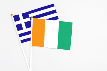 Cote D'Ivoire and Greece stick flags on white background. High quality fabric, miniature national flag. Peaceful global concept.White floor for copy space.