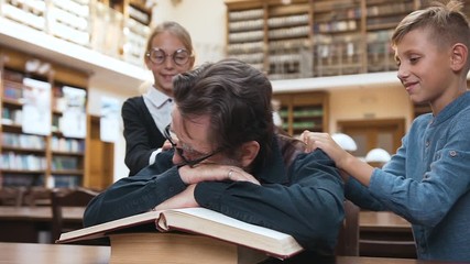 teen schoolchildren waking up their tired respected grandfather that sleeping on books - Powered by Adobe