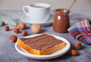 Bread toast with chocolate cream butter, cup of coffee on the concrete background