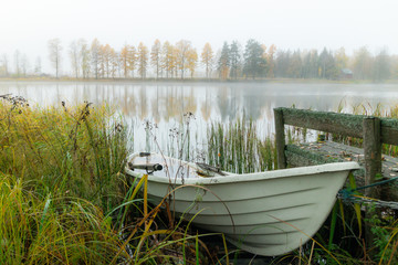 Fototapeta na wymiar Beautiful autumn morning landscape with old rowing boat and Kymijoki river waters. Finland, Kymenlaakso, Kouvola