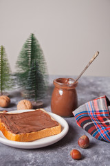 Bread toast with chocolate cream butter with Christmas tree toys on the concrete background