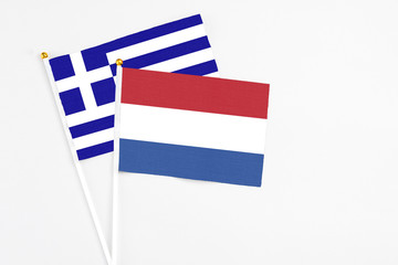 Netherlands and Greece stick flags on white background. High quality fabric, miniature national flag. Peaceful global concept.White floor for copy space.