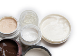 Care products for face, hands and body. Cream in jars on white background