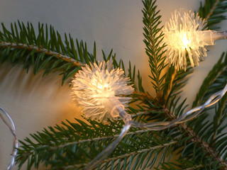 Obraz premium Christmas lights yellow, in the shape of a snowflake, on a green spruce. light background