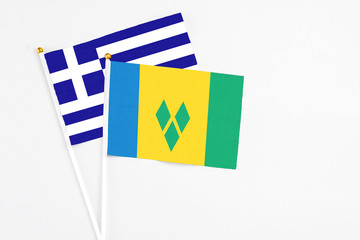 Saint Vincent And The Grenadines and Greece stick flags on white background. High quality fabric,...