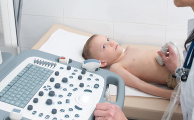 Doctor makes an ultrasound of the abdominal cavity of the child