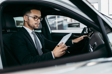 Car seller working in showroom and quality control checking of car details for the last time before buyer comes.