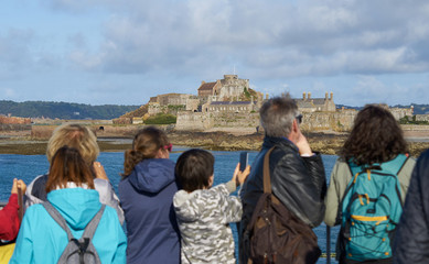 Auf der F&auml;hre vor Elisabeth Castle stehen Touristen an der Reling