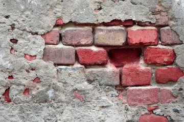 Old ruined wall with sticking out fragments of red bricks and cement