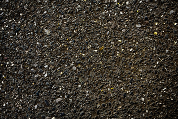 Black asphalt view with inclusion of small golden and white stones - background