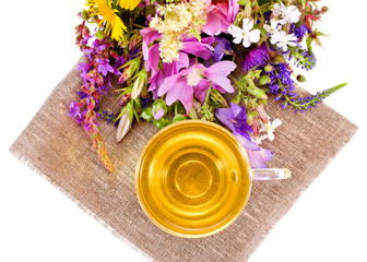 Obraz na płótnie Canvas Cup of tea on a napkin with meadow flowers. Top view.