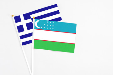 Obraz premium Uzbekistan and Greece stick flags on white background. High quality fabric, miniature national flag. Peaceful global concept.White floor for copy space.