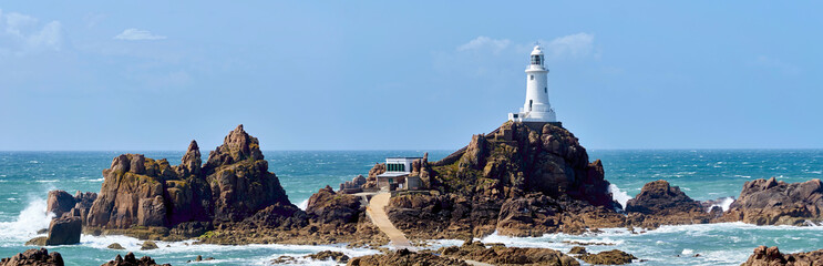La Corbiere Leuchtturm auf Jersey bei Flut und Sonnenschein mit Wellengang