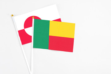 Fototapeta premium Benin and Greenland stick flags on white background. High quality fabric, miniature national flag. Peaceful global concept.White floor for copy space.