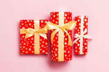 Gift box with gold bow for Christmas or New Year day on pink background, top view