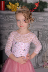 young girl in a pink dress by the fireplace