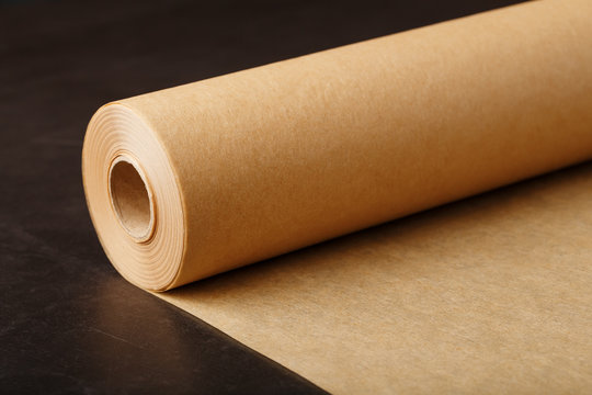 A Roll Of Unfolded Brown Parchment Paper, For Baking Food In On A Dark Background, Top View.