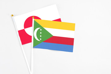 Comoros and Greenland stick flags on white background. High quality fabric, miniature national flag. Peaceful global concept.White floor for copy space.