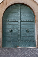 Old wooden door with metal ornaments in the historical part of the Italian capital