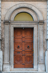 Fototapeta na wymiar wooden door with beautiful wooden ornaments in the historical part of the Italian capital