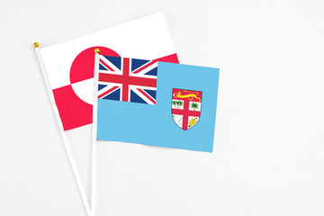 Fiji and Greenland stick flags on white background. High quality fabric, miniature national flag. Peaceful global concept.White floor for copy space.