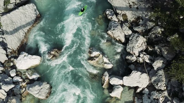 Aerial shot of three white water kayaker running a rapid under the bridge and photographer taking photos of them on a sunny day on Soča River, Slovenia