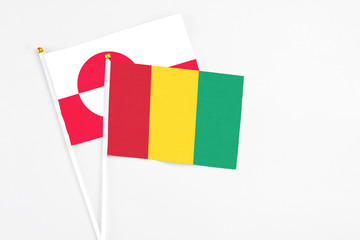 Guinea and Greenland stick flags on white background. High quality fabric, miniature national flag. Peaceful global concept.White floor for copy space.