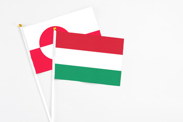 Hungary and Greenland stick flags on white background. High quality fabric, miniature national flag. Peaceful global concept.White floor for copy space.