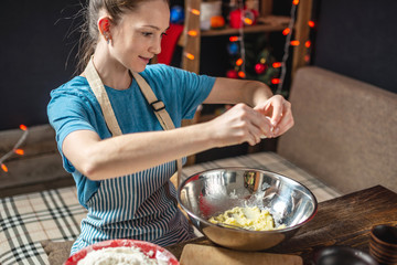 Young woman housewife makes dough for cooking holiday ginger cookies. Home atmosphere in the evening on Christmas eve