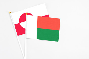 Madagascar and Greenland stick flags on white background. High quality fabric, miniature national flag. Peaceful global concept.White floor for copy space.