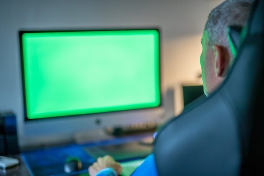 Young man with eyeglasses working at his home desk with green screen - Powered by Adobe